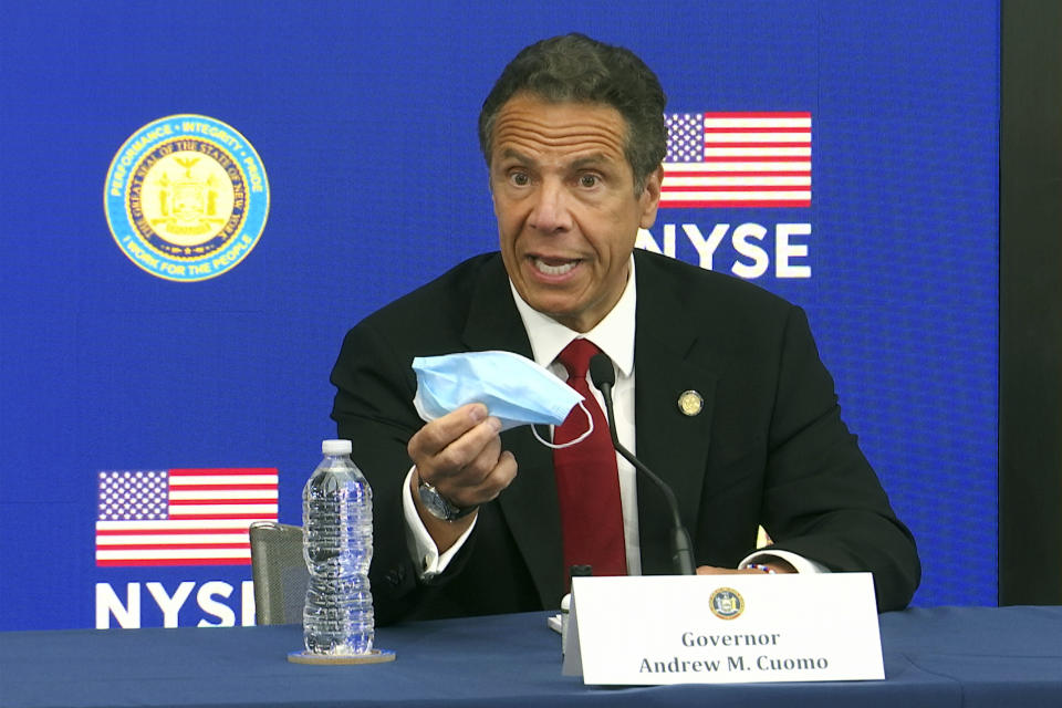 New York Gov, Andrew Cuomo holds his face mask while talking to the media at the New York Stock Exchange, Tuesday, March 26, 2020. Gov. Cuomo rang the opening bell as the trading floor partially reopened during the coronavirus pandemic. (AP Photo/Ted Shaffrey)