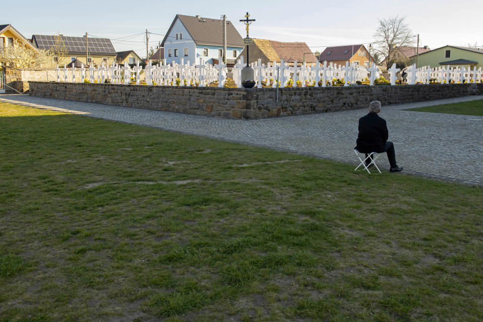 A man celebrates a mass outside of the Church of Saint Catherine in Ralbitz, eastern Germany, Sunday, April 12, 2020. Because the Corona crisis the Easter riders processions have been cancelled. Normally according to a more than hundred years old tradition men of the Sorbs, dressed in black tailcoats ride on decorated horses, proclaiming, singing and praying the message of Jesus' resurrection. The Sorbs are a Slavic German minority located near the German-Polish border. For most people, the new coronavirus causes only mild or moderate symptoms, such as fever and cough. For some, especially older adults and people with existing health problems, it can cause more severe illness, including pneumonia. (AP Photo/Jens Meyer)