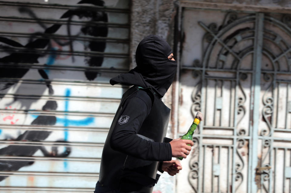 A Bahraini anti-government protester carrying a petrol bomb runs toward riot police during clashes in Dih, on the edge of the capital of Manama, Bahrain, Friday, Feb. 14, 2014. An explosion rocked a bus carrying police in Bahrain on Friday, while security forces used tear gas in clashes with anti-government protesters on the third anniversary of an uprising in the small Gulf island nation. (AP Photo/Hasan Jamali)