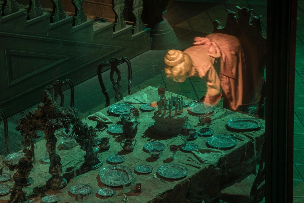 One of the 999 happy haunts at Disneyland's Haunted Mansion attempts to blow out the candle on a birthday cake.