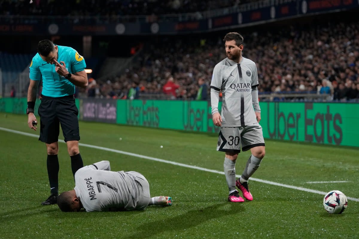 Kylian Mbappe writhes on the floor as Lionel Messi looks on (AP)