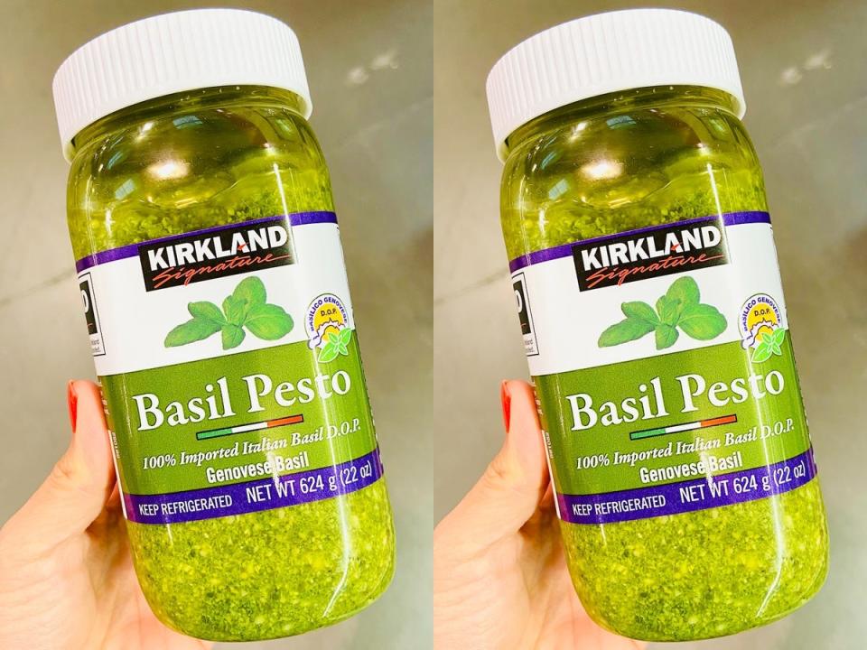 hand holding jar of bright green costco pesto