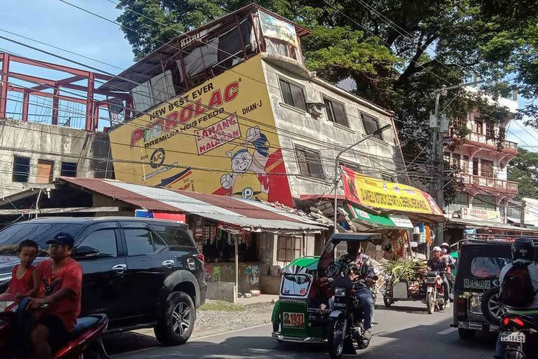 This handout photo taken and released by the Office of Abra Representative Ching Bernos shows people commuting past a damaged building in the municipality of Bangued, in the province of Abra on July 27, 2022, after a 7.0-magnitude earthquake hit the northern Philippines. (Photo by Handout / Office of Abra Representative Ching Bernos / AFP) / RESTRICTED TO EDITORIAL USE - MANDATORY CREDIT "AFP PHOTO / Office of Abra Representative Ching Bernos" - NO MARKETING - NO ADVERTISING CAMPAIGNS - DISTRIBUTED AS A SERVICE TO CLIENTS
