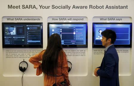 An attendee communicate with SARA, a socially aware robot assistant, during a presentation at the annual meeting of the World Economic Forum (WEF) in Davos, Switzerland, January 17, 2017. REUTERS/Ruben Sprich