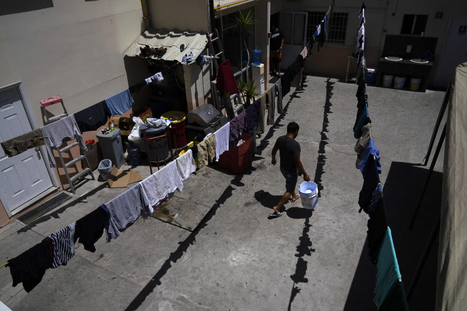 A man carries a bucket at a shelter for migrants applying for asylum in the United States Thursday, June 30, 2022, in Tijuana, Mexico. The Supreme Court has ruled that the Biden administration properly ended a Trump-era policy forcing some U.S. asylum-seekers to wait in Mexico. (AP Photo/Gregory Bull)