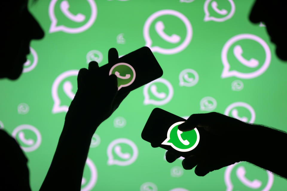 Men pose with smartphones in front of displayed Whatsapp logo in this illustration September 14, 2017. REUTERS/Dado Ruvic