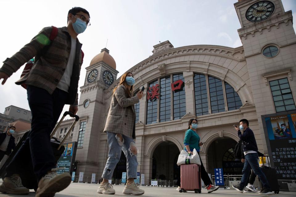 Travelers walk past Wuhan's Hankou railway station a day before it resumes outbound traffic.