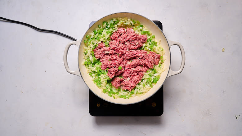 crumbling beef into skillet of vegetables