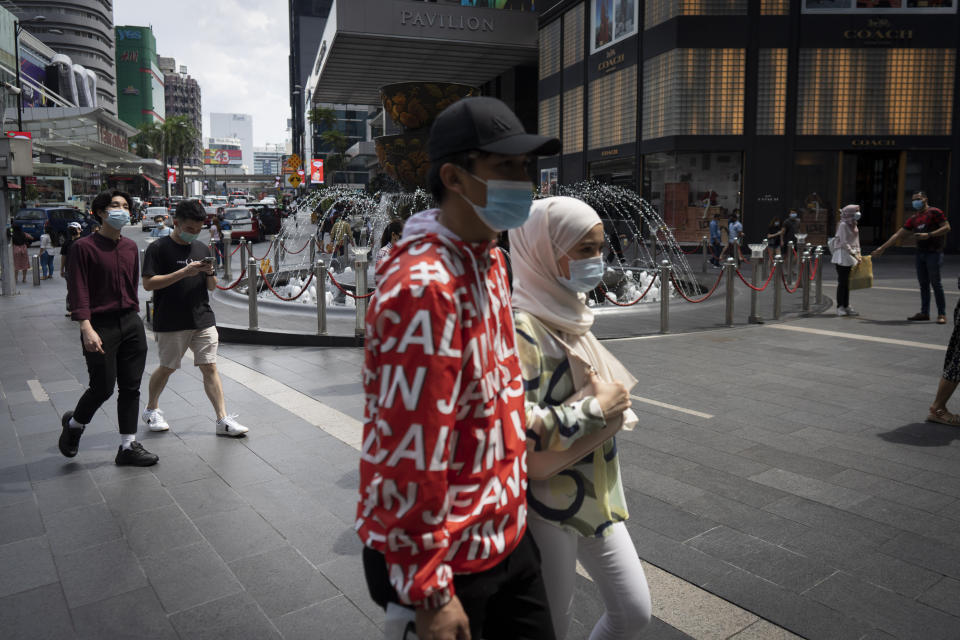 Shoppers wearing face mask walks at a shopping mall in downtown Kuala Lumpur, Malaysia, on Sunday, June 7, 2020. Malaysian government has lifted the conditional movement order (CMCO) and replaced it with a recovery movement control order effective June 10 until Aug. 31. (AP Photo/Vincent Thian)