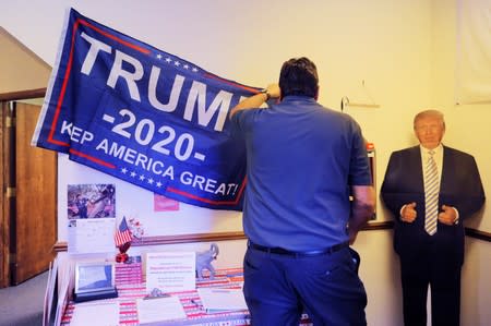 Keith Best puts up a banner next to a cardboard cutout of U.S. President Trump in Waukesha
