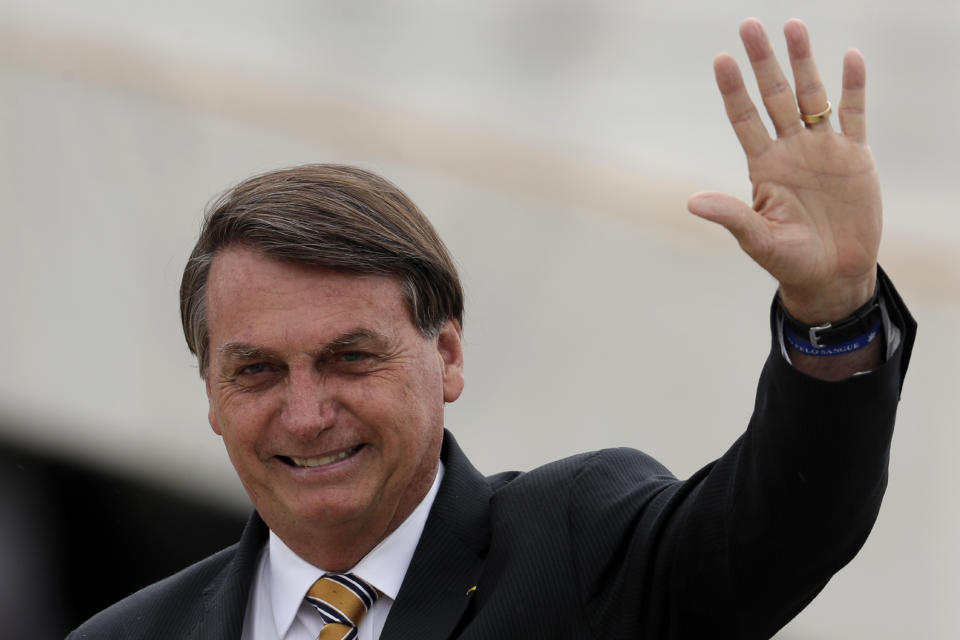 Brazil's President Jair Bolsonaro waves to supporters as he arrives for a ceremony marking National Flag Day at Planalto presidential palace in Brasilia, Thursday, Nov. 19, 2020. (AP Photo/Eraldo Peres)