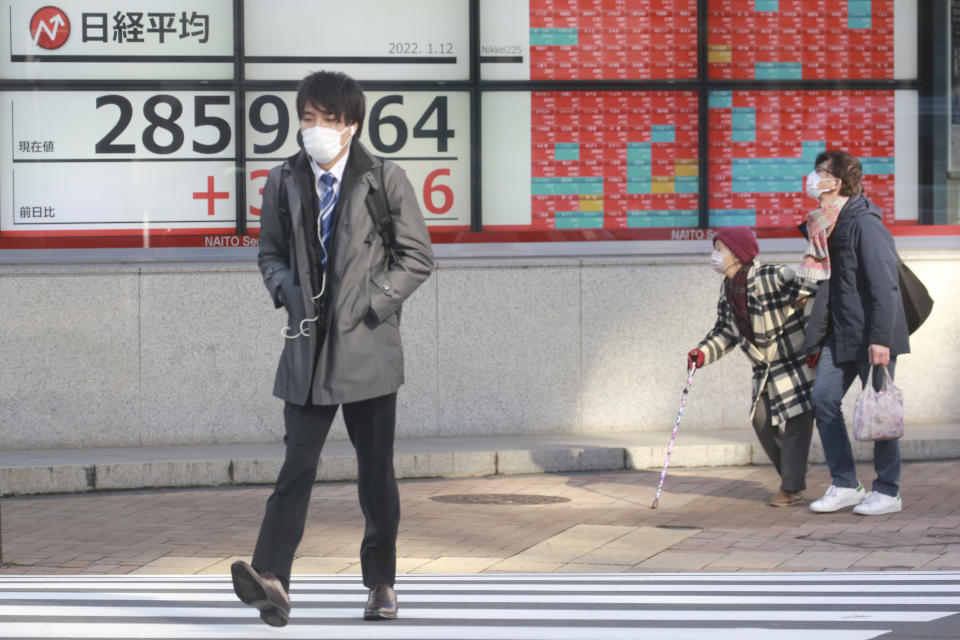 People walk by an electronic stock board of a securities firm in Tokyo, Wednesday, Jan. 12, 2022. Asian stock markets followed Wall Street higher on Wednesday after Federal Reserve chairman Jerome Powell said monetary policy would return to normal and interest rates might be raised earlier than planned.(AP Photo/Koji Sasahara)