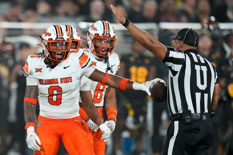 Oklahoma State safety Lyrik Rawls, left, celebrates his interception against Arizona State with cornerback D.J. McKinney (8) as umpire Marlow Fitzgerald, right, signals the turnover during the second half of an NCAA college football game Saturday, Sept. 9, 2023, in Tempe, Ariz. Oklahoma State won 27-15. (AP Photo/Ross D. Franklin)