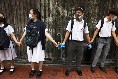 Secondary school students hold a Pepe the Frog plush toy with an eye patch as they form a human chain during a demonstration in Hong Kong