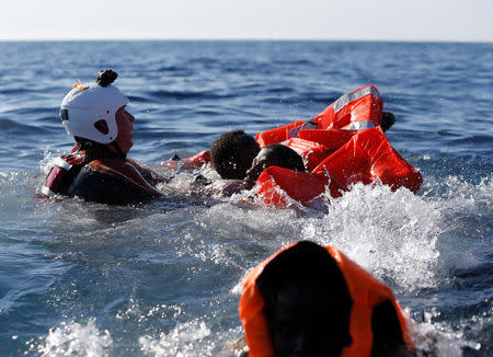 A rescue swimmer holds onto migrants frantically trying to stay afloat after falling off their rubber dinghy during a rescue operation by the Malta-based NGO Migrant Offshore Aid Station (MOAS) ship in the central Mediterranean in international waters some 15 nautical miles off the coast of Zawiya in Libya, April 14, 2017. REUTERS/Darrin Zammit Lupi