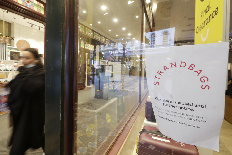 A woman walks past a closed store in Sydney, Wednesday, July 7, 2021. Sydney's two-week lockdown has been extended for another week due to the vulnerability of an Australia population largely unvaccinated against COVID-19, officials said. (AP Photo/Rick Rycroft)