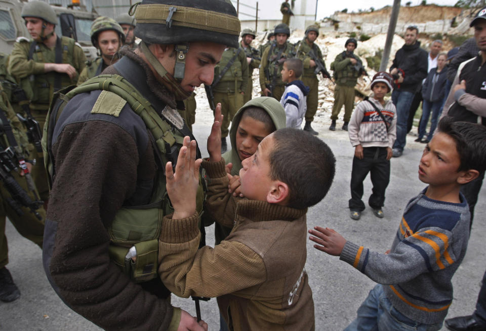 FILE - A Palestinian youth tries to push past an Israeli soldier during a demonstration against Israel's controversial separation barrier in the village of Maasarah near the West Bank city of Bethlehem, April 24, 2009. Israel on Monday, Jan. 31, 2022, called on Amnesty International not to publish an upcoming report accusing it of apartheid, saying the conclusions of the London-based international human rights group are “false, biased and antisemitic.” (AP Photo/Nasser Shiyoukhi, File)