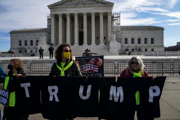 Demonstrators outside the U.S. Supreme Court on Thursday, including Stephen Parlato, 69, of Boulder, Colorado (background), call for Trump to be kept from returning to the Oval Office.
