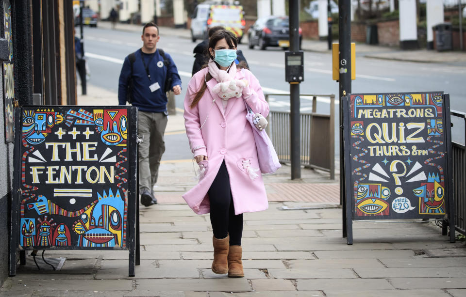 A woman wearing a face mask walks past pub signs in Leeds, West Yorkshire, the day after Prime Minister Boris Johnson called on people to stay away from pubs, clubs and theatres, work from home if possible and avoid all non-essential contacts and travel in order to reduce the impact of the coronavirus pandemic.