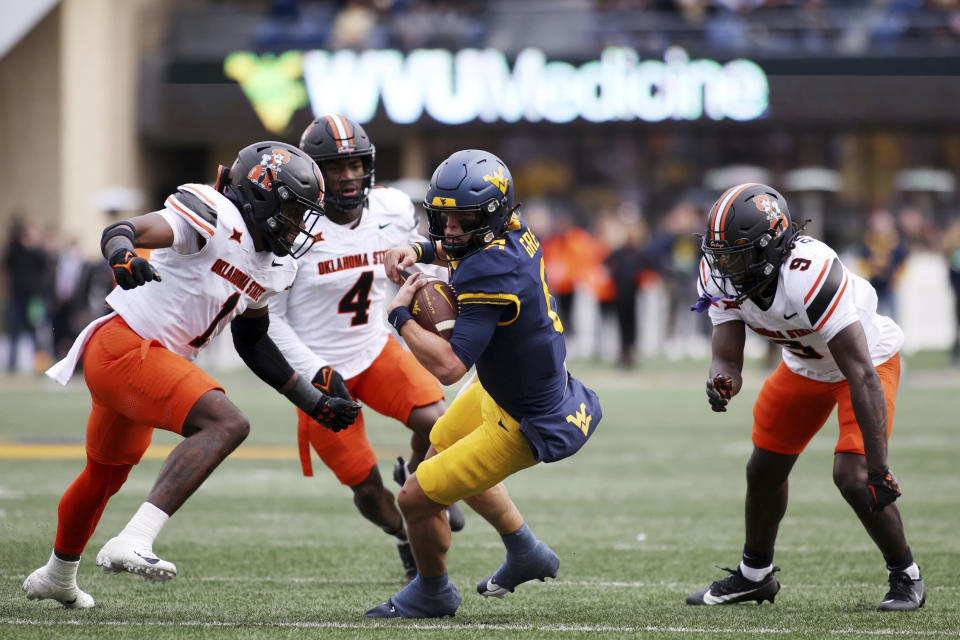 West Virginia quarterback Garrett Greene, center, eludes three Oklahoma State defenders during the first half of an NCAA college football game Saturday, Oct. 21, 2023, in Morgantown, W.Va. (AP Photo/Chris Jackson)