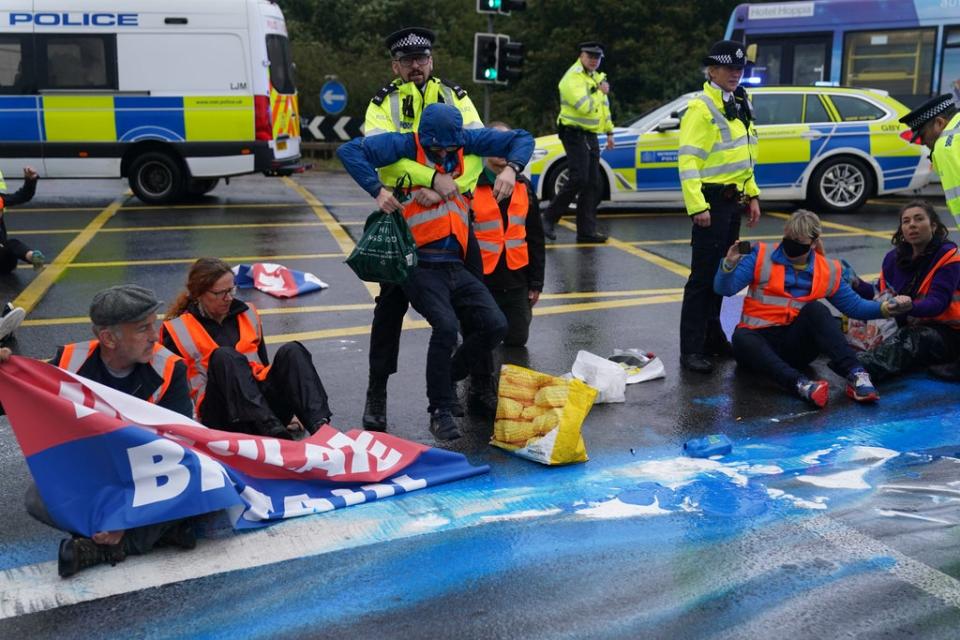 Police officers detain protesters from Insulate Britain occupying a roundabout leading from the M25 motorway to Heathrow Airport in London (Steve Parsons/PA) (PA Wire)