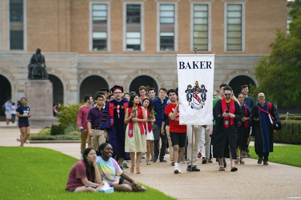 In this March 13, 2020 photo, seniors at Rice University parade toward the school's main archway, known as the Sallyport, to continue a commencement tradition at the school in Houston. Due to the coronavirus outbreak it's not clear whether the campus will reopen in time for graduation. The new coronavirus causes mild or moderate symptoms for most people, but for some, especially older adults and people with existing health problems, it can cause more severe illness or death. (Jeff Fitlow/Rice University via AP)