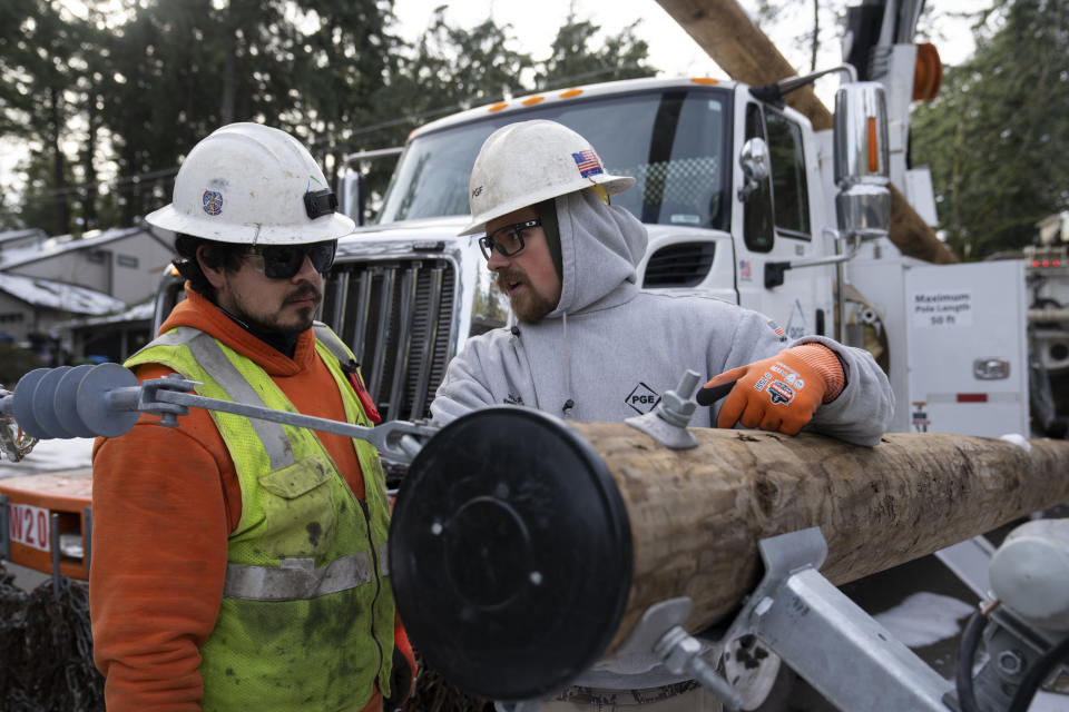 Workers from PG&E talk as they work on restoring power to the area after a storm on Tuesday, Jan. 16, 2024, in Lake Oswego, Ore. (AP Photo/Jenny Kane)