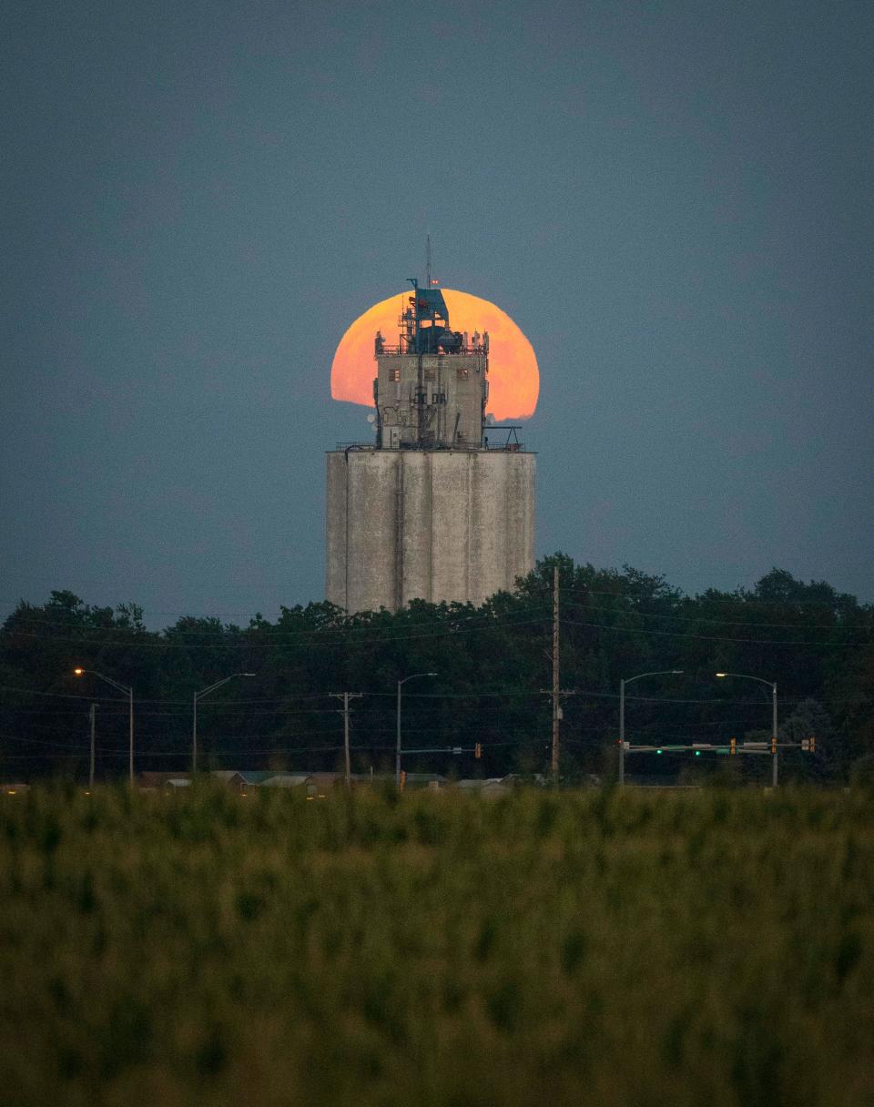 The moon rises behind a grain elevator in Waukee.