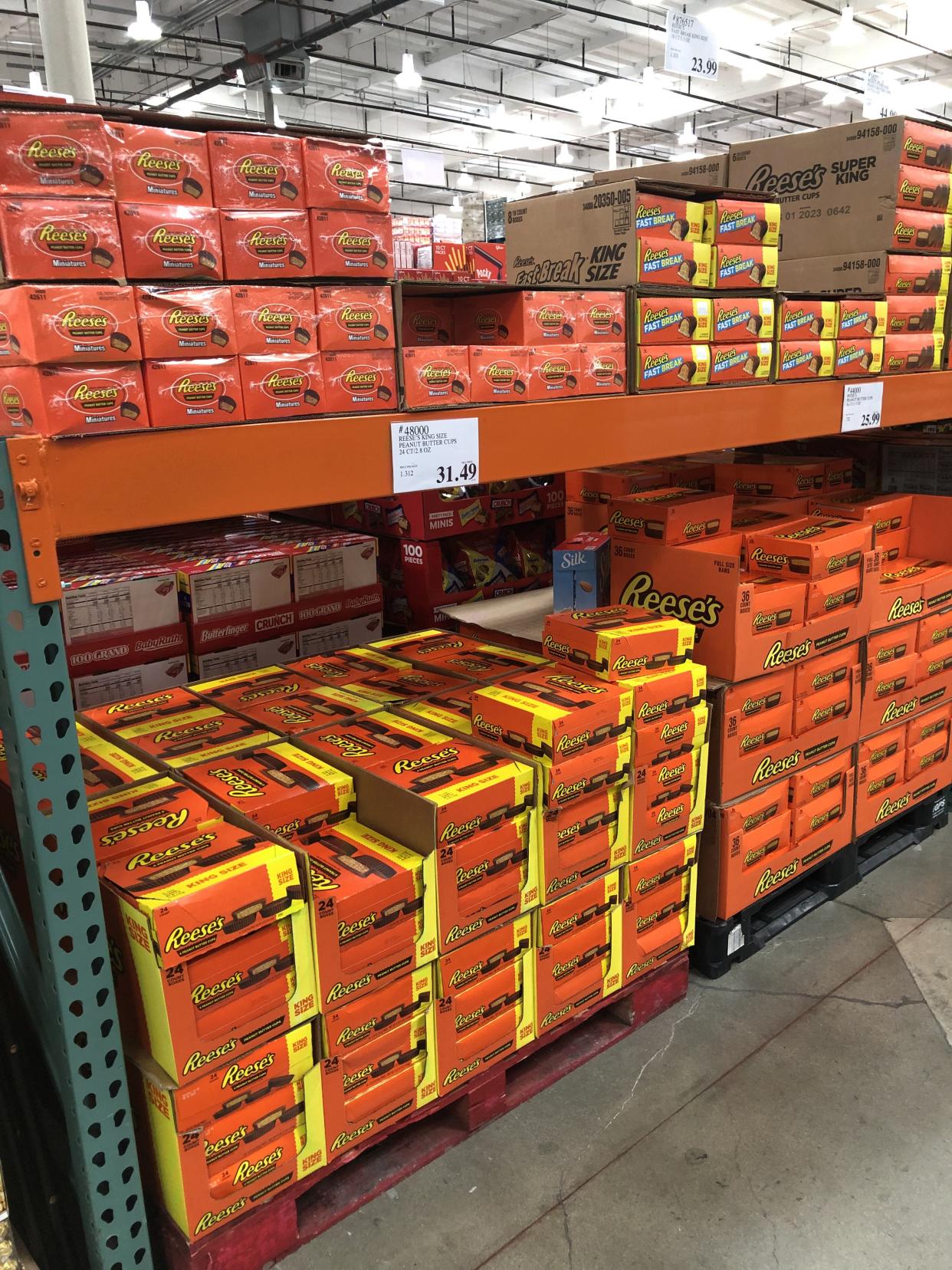 Many plus-sized packages of Reese's candy products are shown stacked at a Costco Business Center
