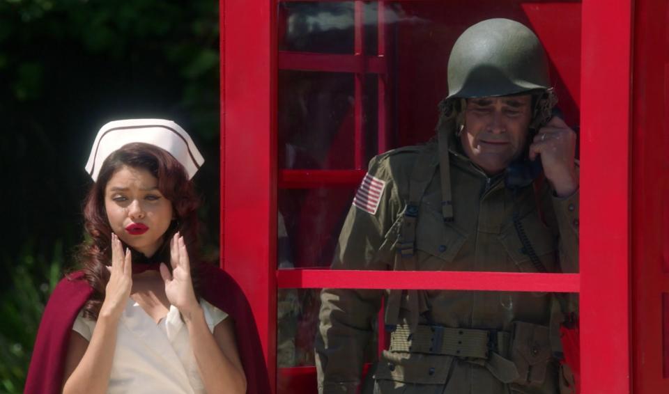 Haley poses next to Phil's phone booth while he's inside crying