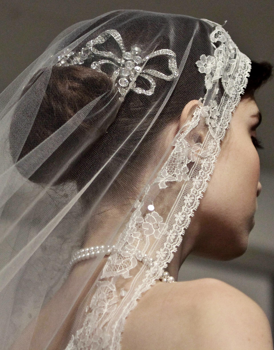 A model presents a bridal fashion creation from the Oscar de la Renta collection, in New York, Monday, April 22, 2013. (AP Photo/Bebeto Matthews)