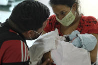 Ada Mendoza, 24, shows her daughter Peyton to her partner Leo Camejo for the first time, hours after giving birth at the Hugo Chavez Frias Public Maternity and Children's Hospital, in the El Valle neighborhood of Caracas, Venezuela, Thursday, Sept. 10, 2020. Mendoza said her daughter has her father's nose. (AP Photo/Matias Delacroix)