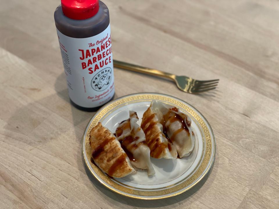 pan-fried potstockers on a plate in front of a bottle of barbecue sauce