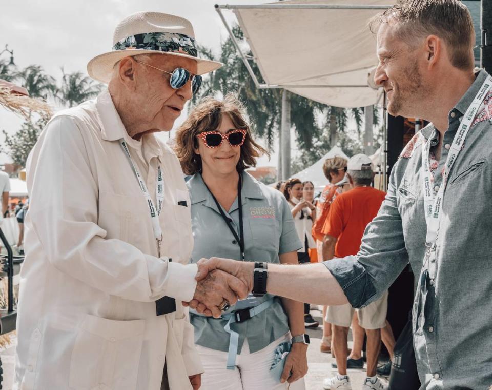 El presidente del Festival de las Artes de Coconut Grove, Monty Trainer, y la directora ejecutiva, Camille Marchese, estrechan la mano del artista Benjamin Frey en el festival.