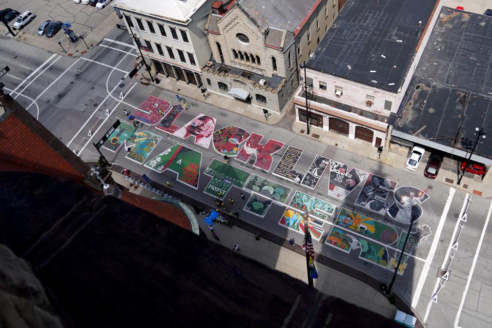 Artists and community members touch up the Black Lives Matter! Mural along Plum Street in front of City Hall, Wednesday, June 15, 2022, in Cincinnati. Artists with Black Art Speaks and community volunteers refreshed the outline of each letter.