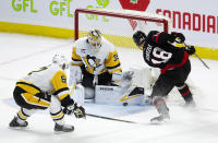 Ottawa Senators center Tim Stutzle tries to put the puck past Pittsburgh Penguins goaltender Tristan Jarry under pressure from center Sidney Crosby during overtime in an NHL hockey game, Tuesday, March 12, 2024, Ottawa, Ontario. (Adrian Wyld/The Canadian Press via AP)