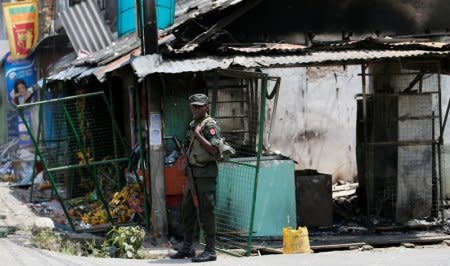 Sri Lanka's army soldier stands guard next to a damaged shop after a clash between two communities in Digana, central district of Kandy, Sri Lanka March 8, 2018. REUTERS/Dinuka Liyanawatte/File Photo