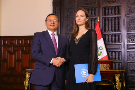 Peruvian Foreign Minister Nestor Popolizio (L) shakes hands with U.N. Refugee Agency’s special envoy Angelina Jolie at the government palace in Lima, Peru October 23, 2018. Courtesy of Peruvian Government Palace/Andres Valle/Handout via REUTERS