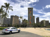 A police officer arrives to tell people to leave Waikiki Beach in Honolulu on Saturday, March 28, 2020. Like many cities across the world, Honolulu came to an eerie standstill this weekend as the coronavirus pandemic spread throughout the islands. But Hawaii officials went beyond the standard stay-at-home orders and effectively flipped the switch on the state's tourism-fueled economic engine in a bid to slow the spread of the virus. As of Thursday, anyone arriving in Hawaii must undergo a mandatory 14-day self-quarantine. The unprecedented move dramatically reduced the number of people on beaches, in city parks and on country roads where many people rely on tourism to pay for the high cost of living in Hawaii. (AP Photo/Caleb Jones)