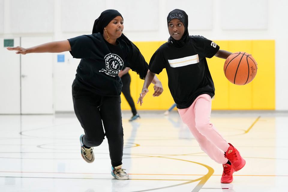 Fardowsa Haji, 13, dribbles past Ithan Abdulkadir, 14, during a Neighborhood Athletics basketball practice Tuesday at Sullivant Elementary on the West Side.