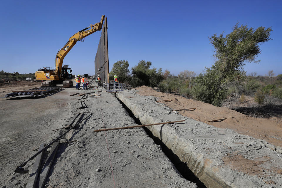 FILE - In this Sept. 10, 2019, file photo government contractors erect a section of Pentagon-funded border wall along the Colorado River, in Yuma, Ariz. A federal appeals court hears arguments against diverting Pentagon money for border wall construction as time runs out. It says the Trump administration has moved quickly to spend the money after the Supreme Court rejected an emergency appeal to prevent work from starting in July. cut to pay for President Donald Trump's wall. (AP Photo/Matt York, File)