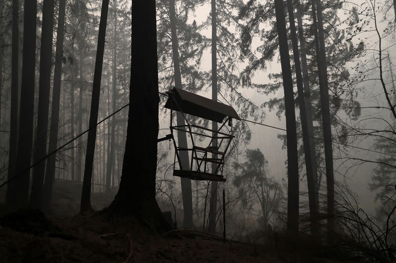 The remains of a fire damaged chairlift hangs as smoke billows in the aftermath of the Beachie Creek fire near Detroit, Oregon