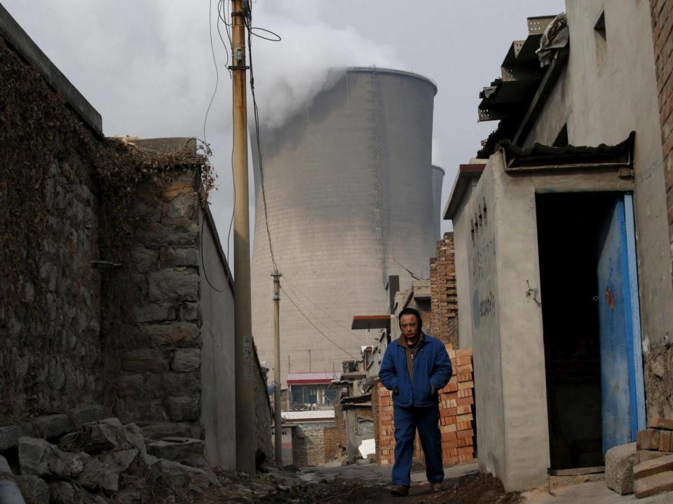 A man makes his way at a village which locates next to cooling towers of a coal-fired power plant in Shijiazhuang, Hebei province, China (Reuters)