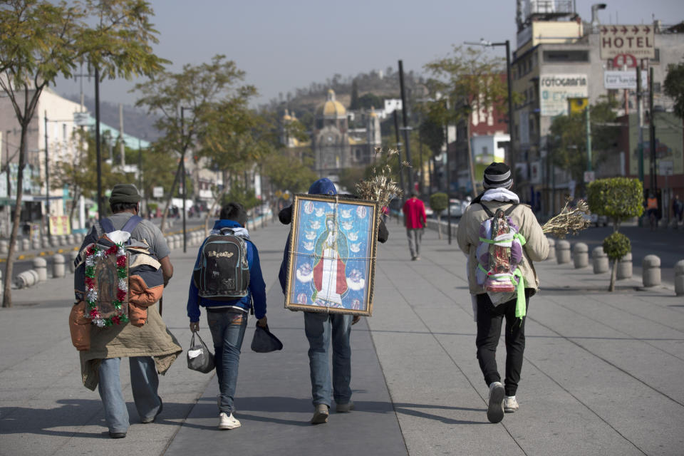 FILE - Alejandro Gonzalez carries an image of the Virgin of Guadalupe on his back as he makes a pilgrimage along with his family and friends to the Basilica of the Virgin of Guadalupe, which was originally known as El Tepeyac and is a protected natural area, in Mexico City, Dec. 9, 2020. Environmentalists say the administration of President Andrés Manuel López Obrador is trying to greenwash its legacy by adding dozens of new protected natural areas while simultaneously slashing funding for the environmental protection department. (AP Photo/Marco Ugarte, File)