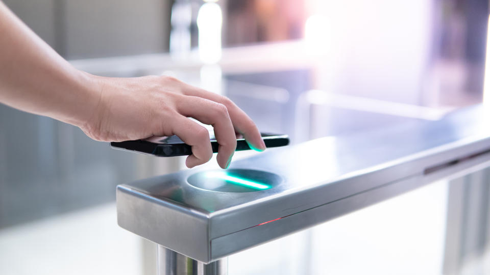 Male hand using smartphone to open automatic gate machine in office building