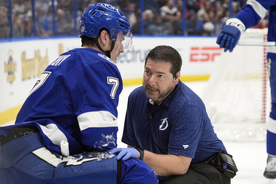Tampa Bay Lightning defenseman Haydn Fleury (7) talks to trainer Tom Mulligan after he was shaken up on a check by Washington Capitals right wing Tom Wilson during the first period of an NHL hockey game Thursday, Feb. 22, 2024, in Tampa, Fla. (AP Photo/Chris O'Meara)
