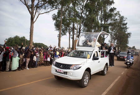 Pope Francis waves to people lined along the road as he heads to lead a mass at the Uganda Martyrs' shrine in Namugongo, Uganda, November 28, 2015. REUTERS/Edward Echwalu