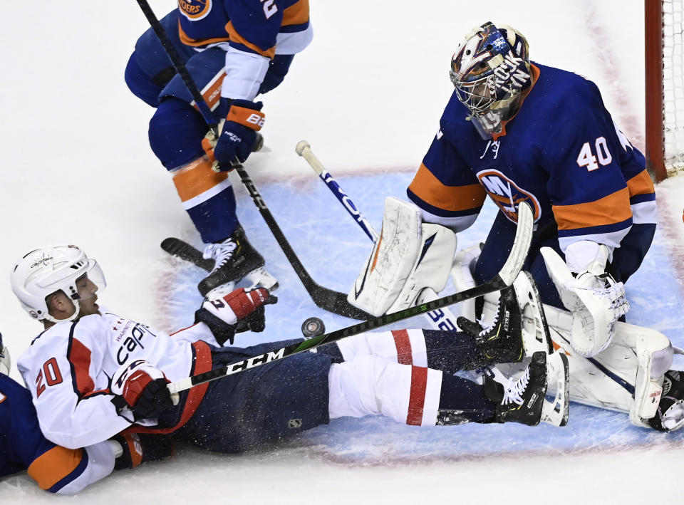 Washington Capitals center Lars Eller (20) battles for the puck against New York Islanders goaltender Semyon Varlamov (40) during third-period NHL Eastern Conference Stanley Cup playoff hockey action in Toronto, Sunday, Aug. 16, 2020. (Nathan Denette/The Canadian Press via AP)