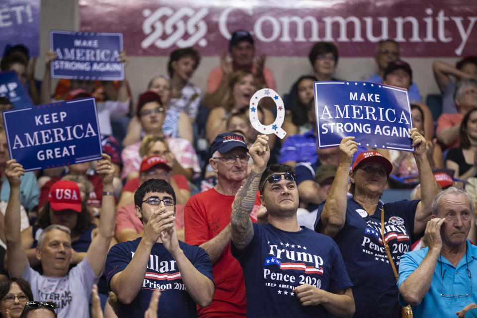 Un hombre levanta un símbolo del movimiento de la teoría de la conspiración QAnon en medio de pancartas con eslóganes de apoyo al entonces presidente Donald Trump en un acto de campaña en Avoca, Pensilvania, el 2 de agosto de 2018. (Al Drago/The New York Times)