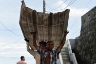 <p>Residents from La Perla carry a piece of metal through the streets after Hurricane Maria, in San Juan, Puerto Rico, Monday, Sept. 25, 2017. The island territory of more than 3 million U.S. citizens is reeling in the devastating wake of Hurricane Maria. (Photo: Carlos Giusti/AP) </p>